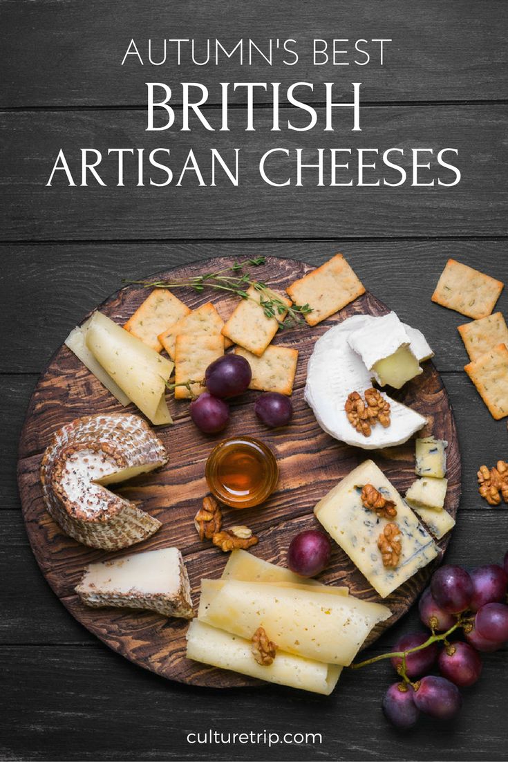 an autumn's best british artisan cheeses on a wooden platter with grapes and crackers