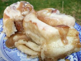 a blue and white plate topped with donuts covered in icing on top of grass