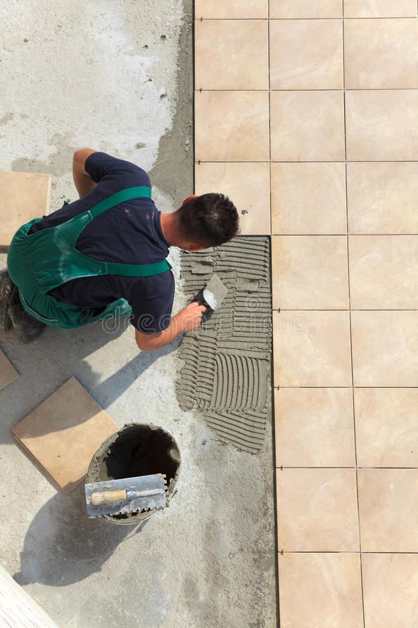 a man in overalls is working on a tile floor next to a drain hole