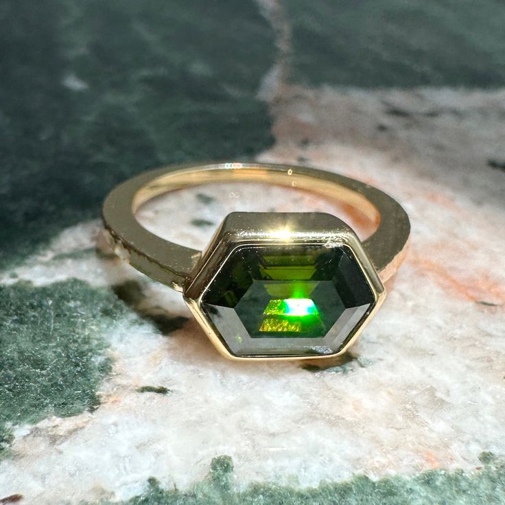 Just the unique piece your ring stack is calling for. Slip our Enchanting Hex Ring on and suddenly everything looks more on point! She features an eye catching faceted olive green crystal upon a bold band. Synthetic crystal measures 8mm x 11.5mm. Our materials make for an amazing, high quality, seamless, jewelry piece with longevity. Our rings are plated with 18k gold, 18k rose gold, or sterling silver and finished with a protective coating. A little secret we’ll keep between us: it looks way mo Modern Green Crystal Ring As A Gift, Modern Green Crystal Ring As Gift, Faceted May Birthstone Ring Jewelry, Modern Green Crystal Ring For Gift, Green Crystal Open Ring Stackable, Green Stackable Open Crystal Ring, Modern Green Crystal Gemstone Ring, Modern Green Gemstone Stackable Rings, Green Emerald Open Ring With Vs Clarity