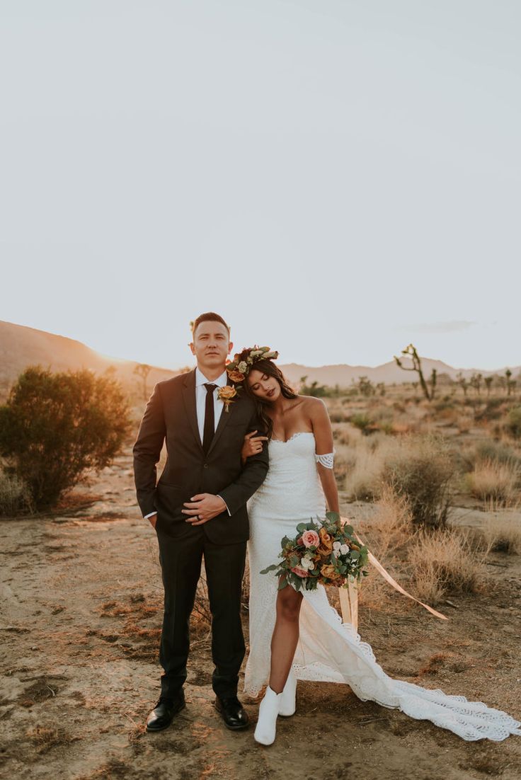 a bride and groom pose for a photo in the desert at their wedding day,