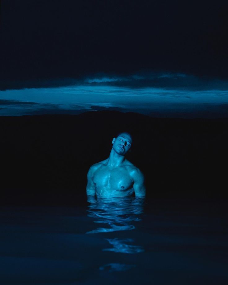 a man is floating in the water at night with his head above the water's surface