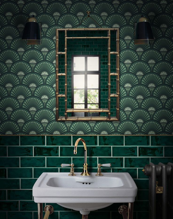 a white sink sitting under a mirror next to a green tiled wall with gold accents