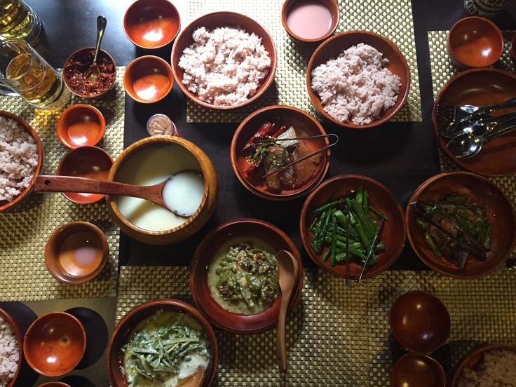 many bowls and spoons with food in them on a table top next to glasses