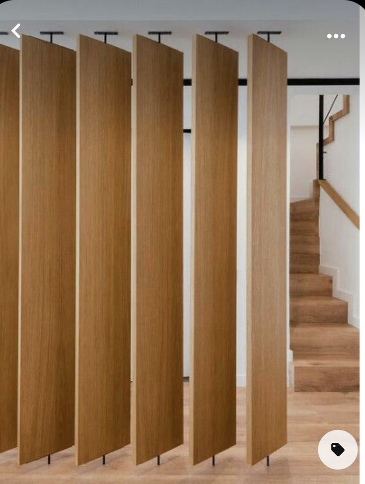 a room divider made out of wood in front of stairs and wooden flooring