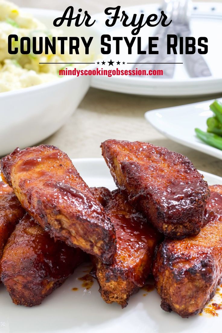 air fryer country style ribs on a white plate with green beans in the background