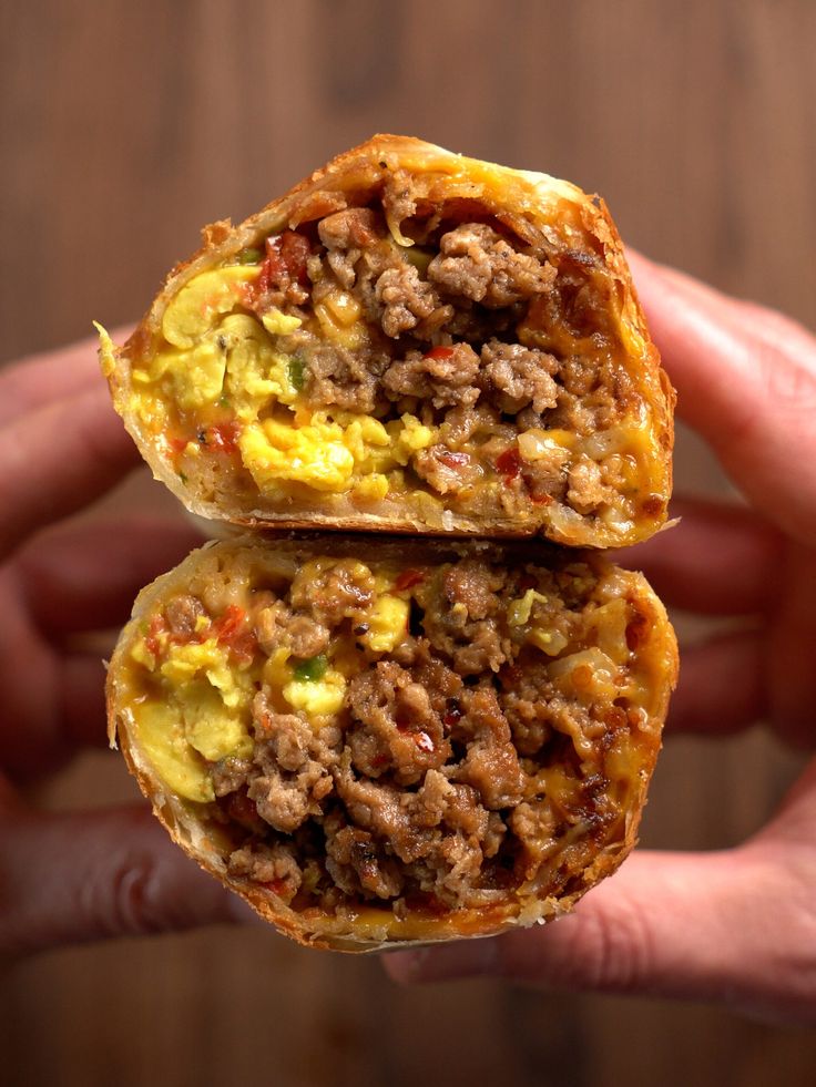 two breakfast sandwiches are stacked on top of each other in the palm of someone's hand