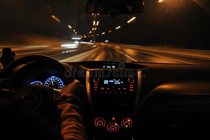 a car driving down a highway at night with the lights on and dashboard illuminated up