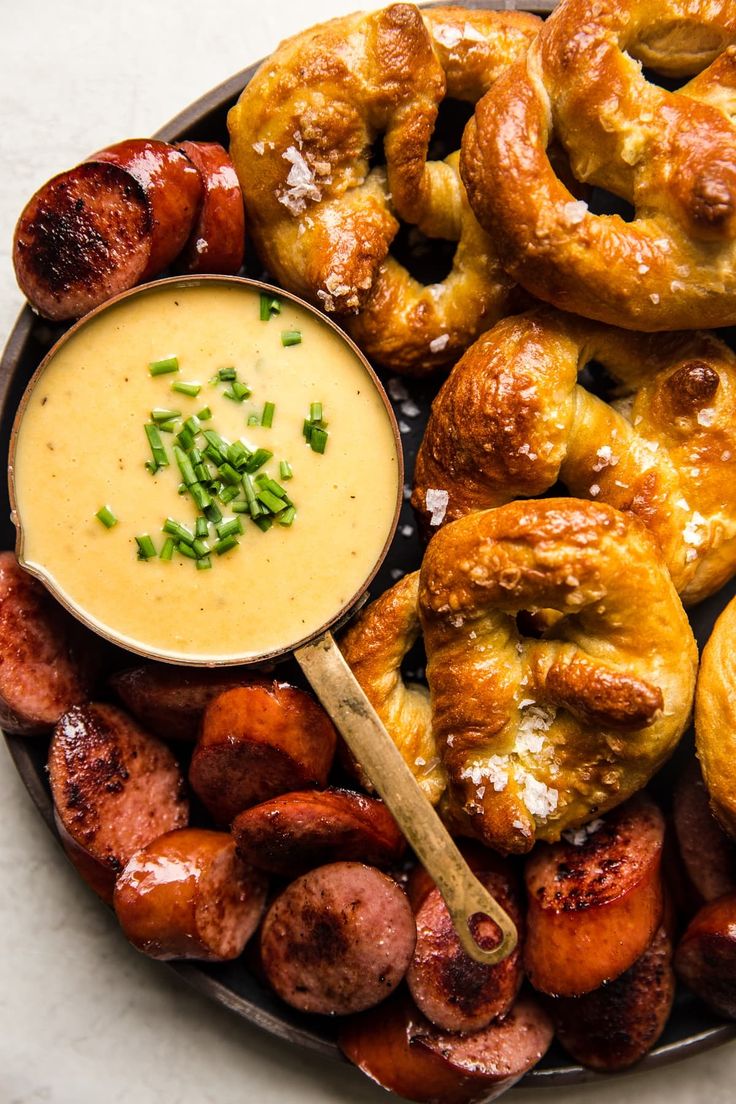 a plate full of sausages, pretzels and dipping sauce