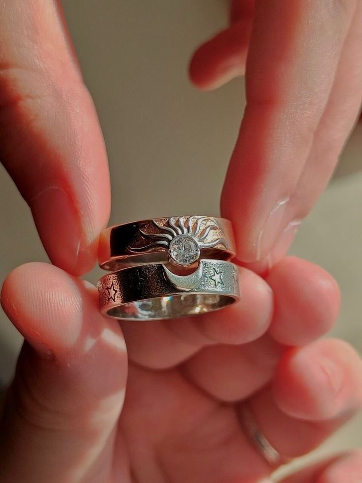 a person holding three different rings in their hands, one with a sun design on it