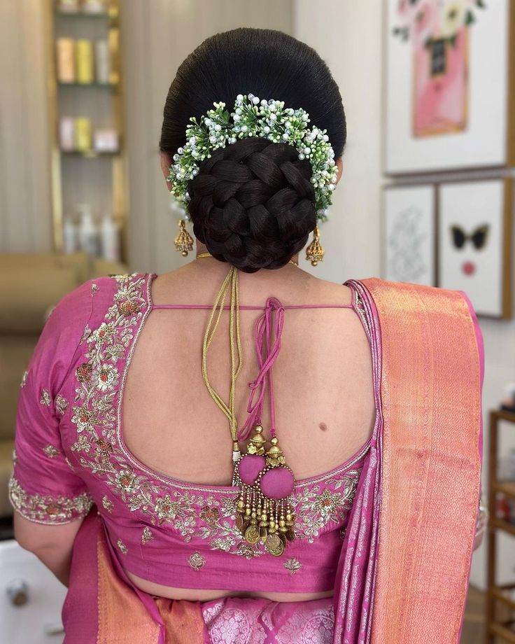 a woman wearing a pink sari with flowers in her hair and jewelry on her neck