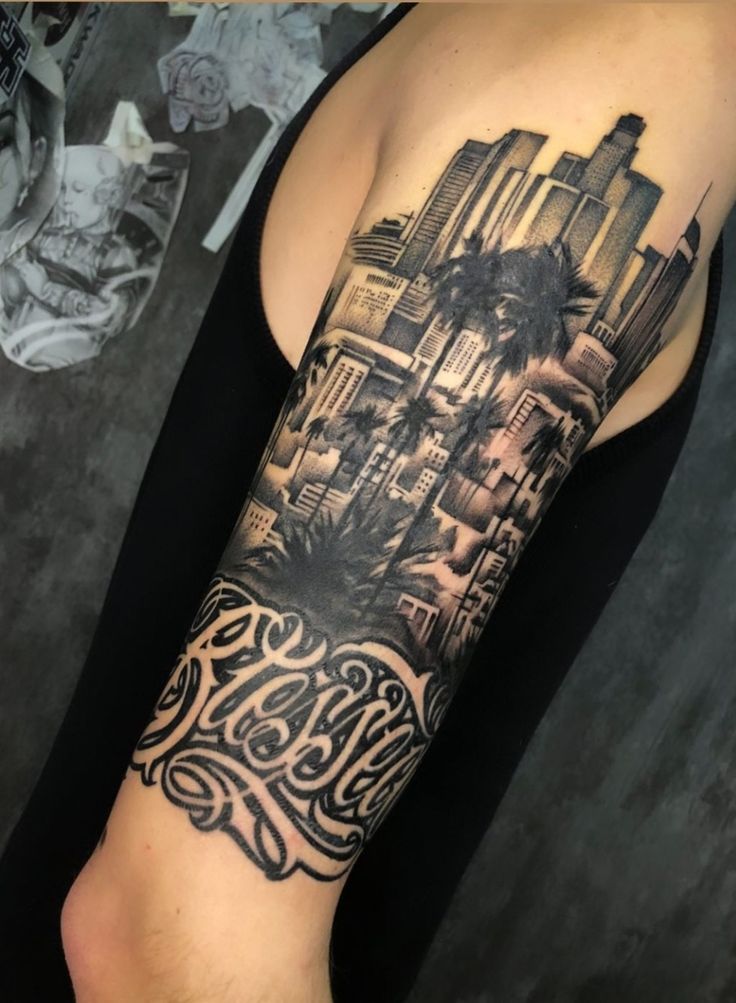 a man's arm with a city skyline and palm trees tattoo on the forearm