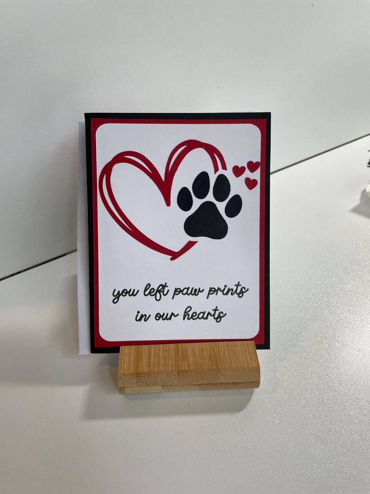 a card with a dog's paw prints on it and a wooden stand holding the card