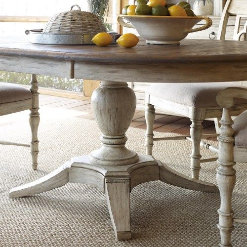 a bowl of fruit is on the table in front of some chairs and a vase