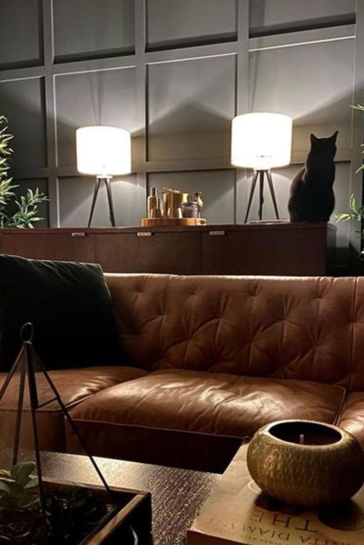 a brown leather couch in a living room with two lamps on either side of it