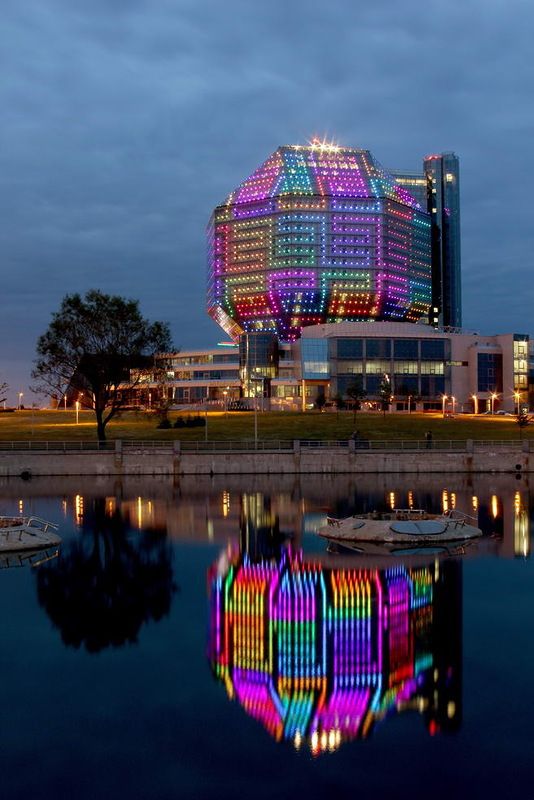 a building that is lit up in the night with colorful lights on it's side