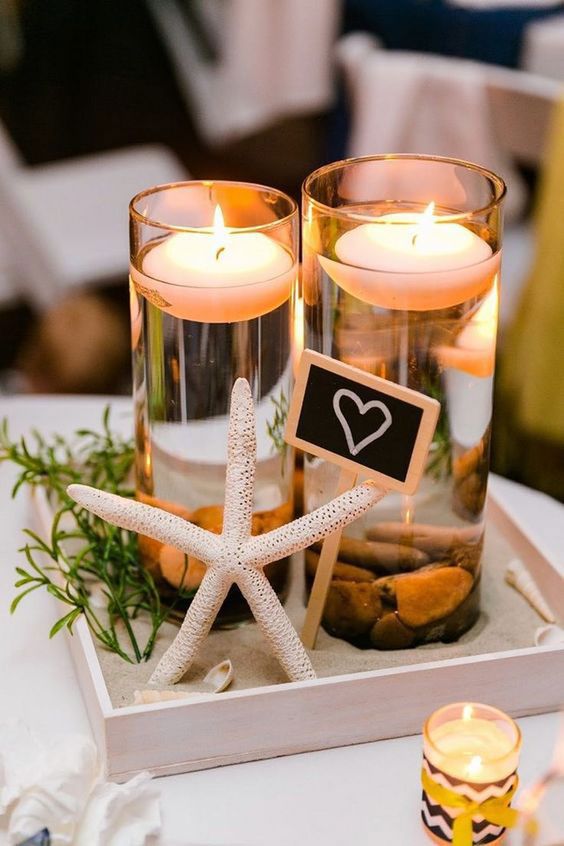 two candles are sitting on a tray with starfish and other items around it,