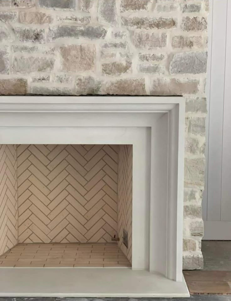 an empty fireplace in front of a brick wall with white paint on the top and bottom