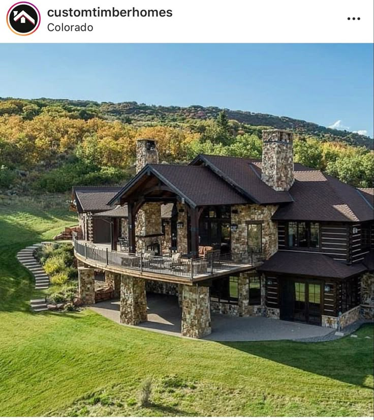 an aerial view of a home in the mountains with stone pillars and large porches