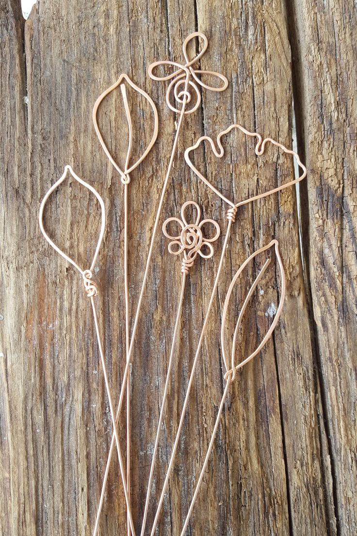 a bunch of wire flowers sitting on top of a piece of wooden planked wood