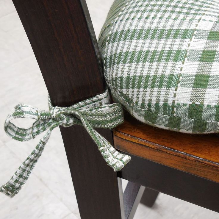 a green and white checkered pillow tied to a wooden chair