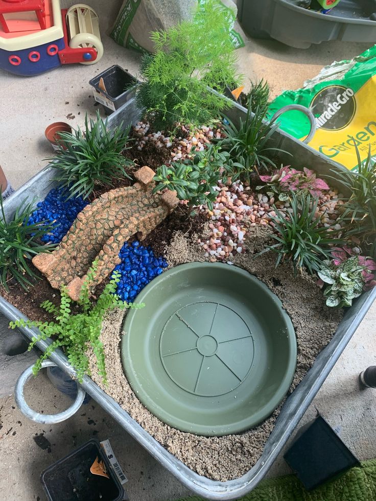 an assortment of plants and rocks in a plastic container on the floor next to toys