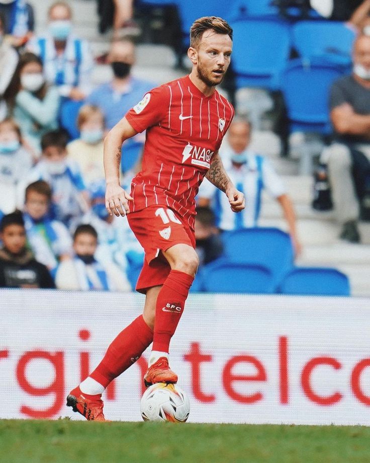 a soccer player is running with the ball in his hand and fans are behind him