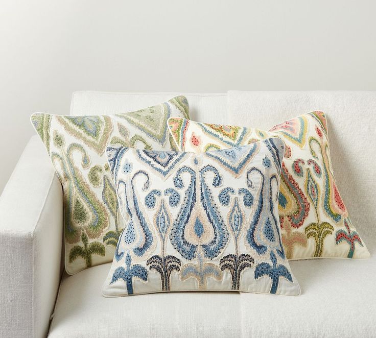 three decorative pillows on a white couch