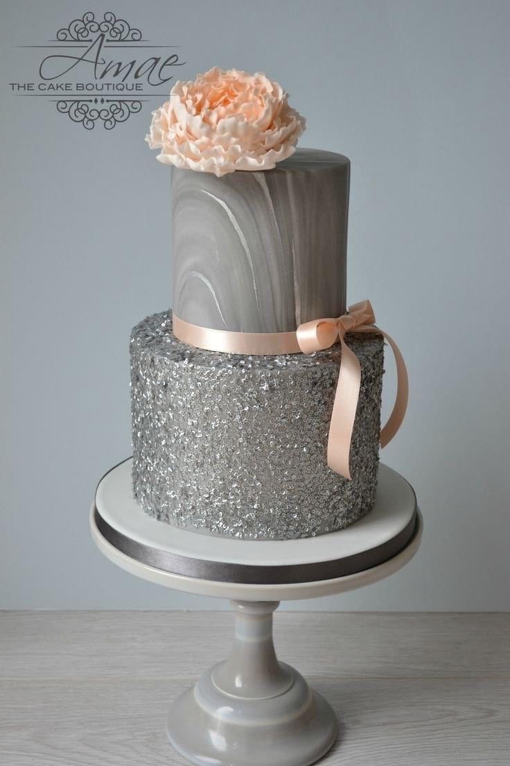 a three tiered cake decorated with silver and pink icing, topped with a flower