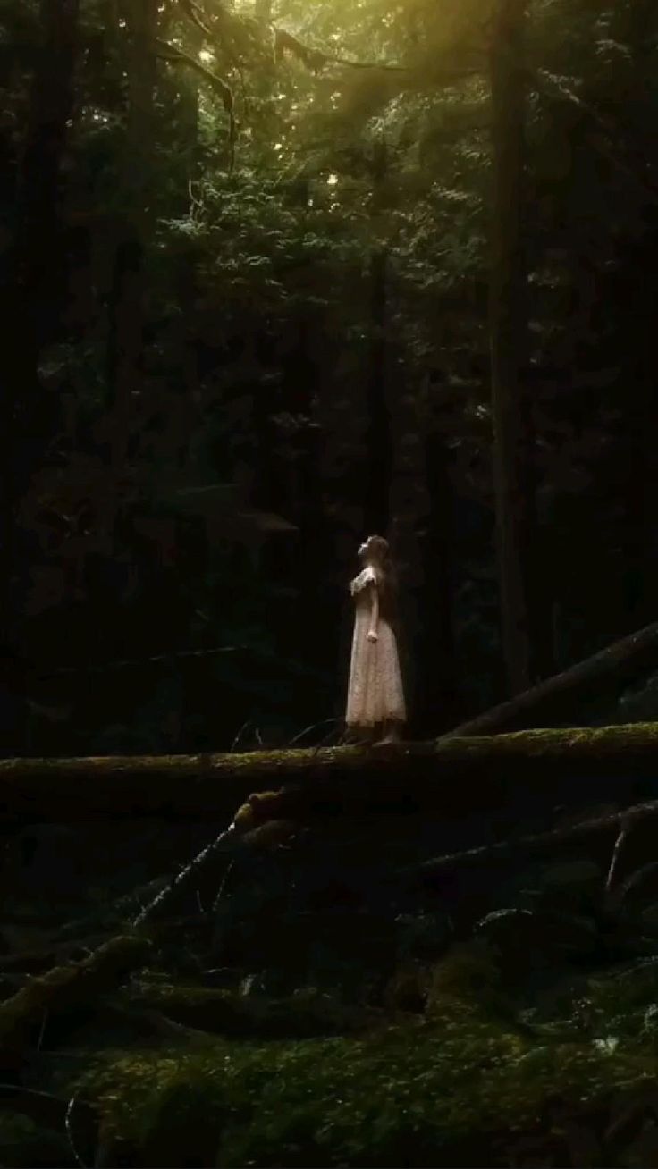 a woman standing in the middle of a forest