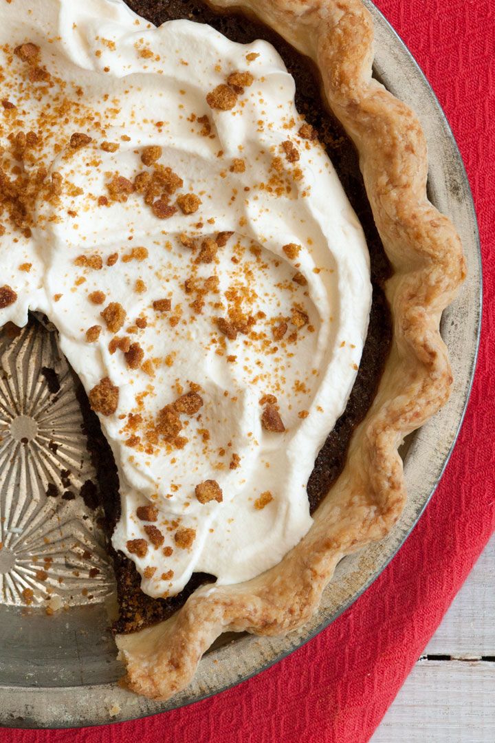 a pie sitting on top of a metal pan covered in frosting and toppings