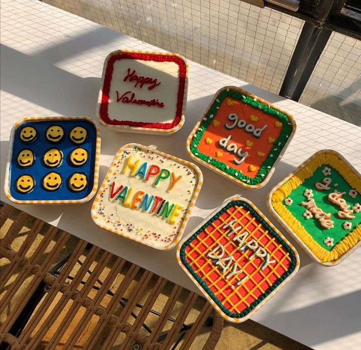 four decorated cookies sitting on top of a table next to each other with happy valentine's day written on them