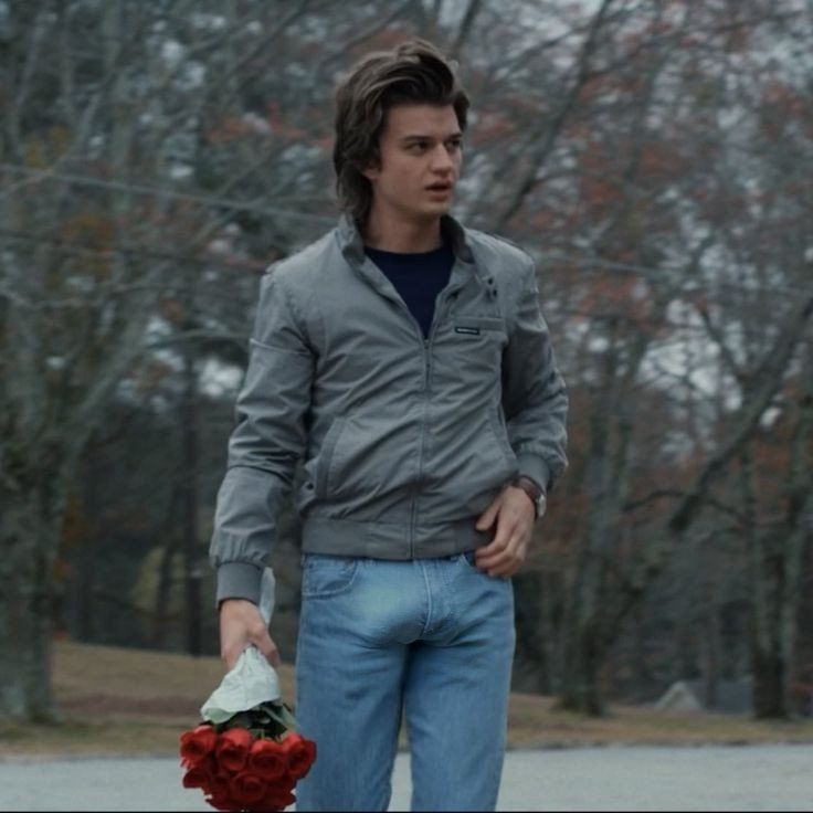 a young man walking down the street with flowers in his hand