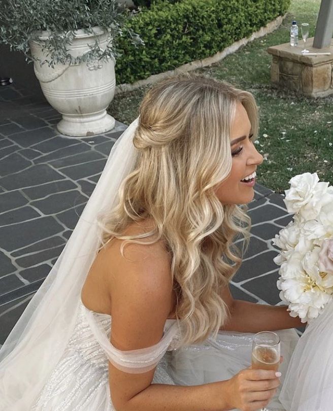 a woman in a wedding dress is holding a bouquet and looking at another woman's face