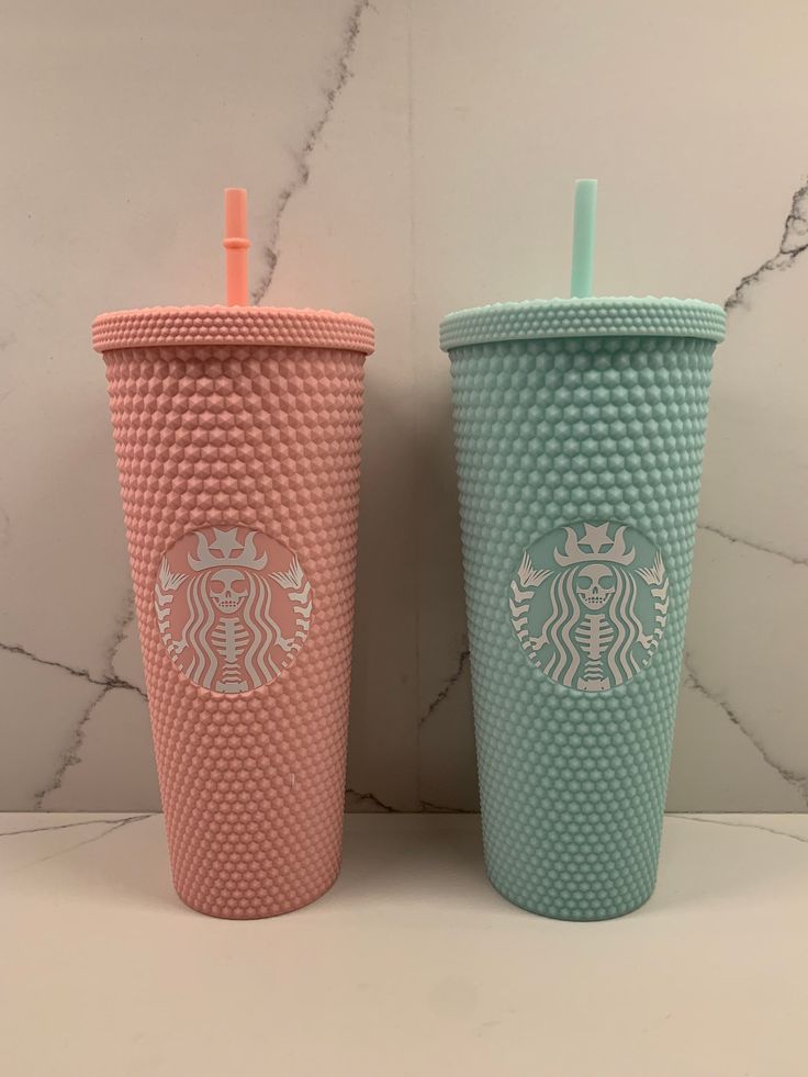 two starbucks cups sitting side by side next to each other on a marble counter top