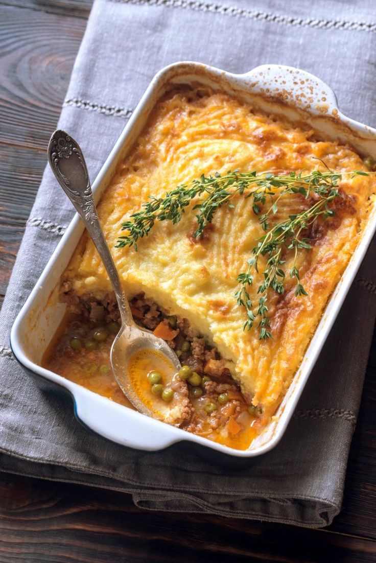 a casserole with meat and vegetables in a white dish on a blue napkin