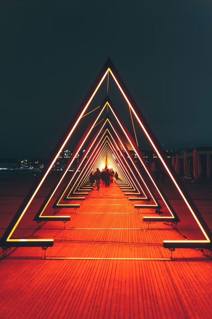 a long exposure photo of people sitting on benches in the middle of a walkway at night