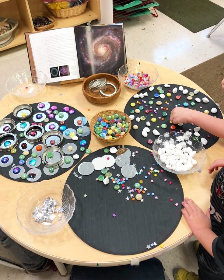 two children are sitting at a table making crafts