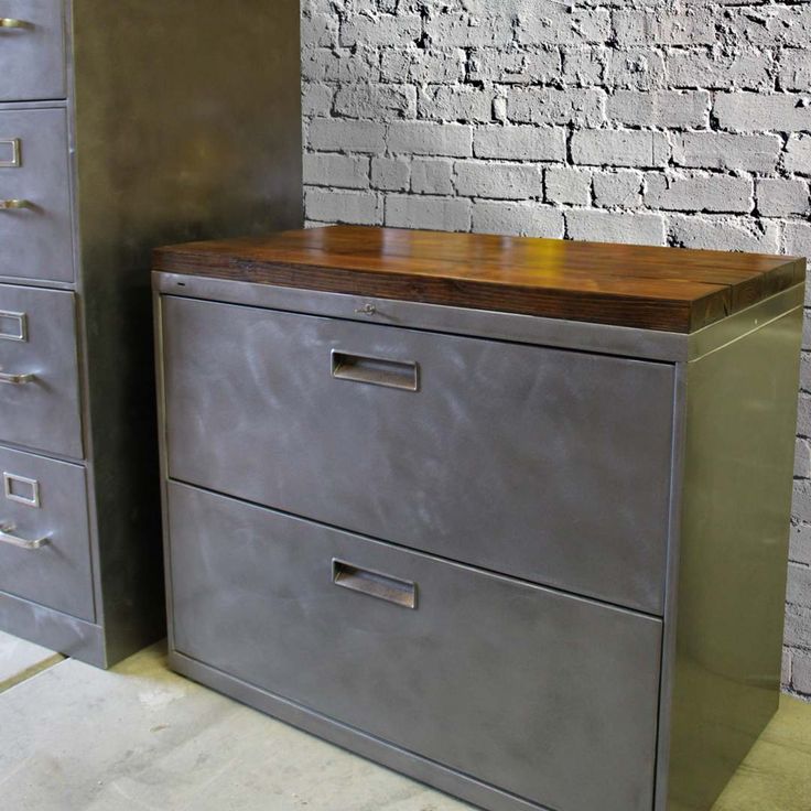 two metal filing cabinets sitting next to each other in front of a brick wall and floor