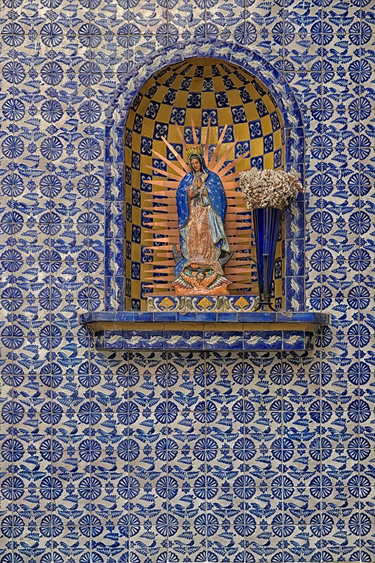 an ornate blue and yellow wall with a statue on the window sill in front of it