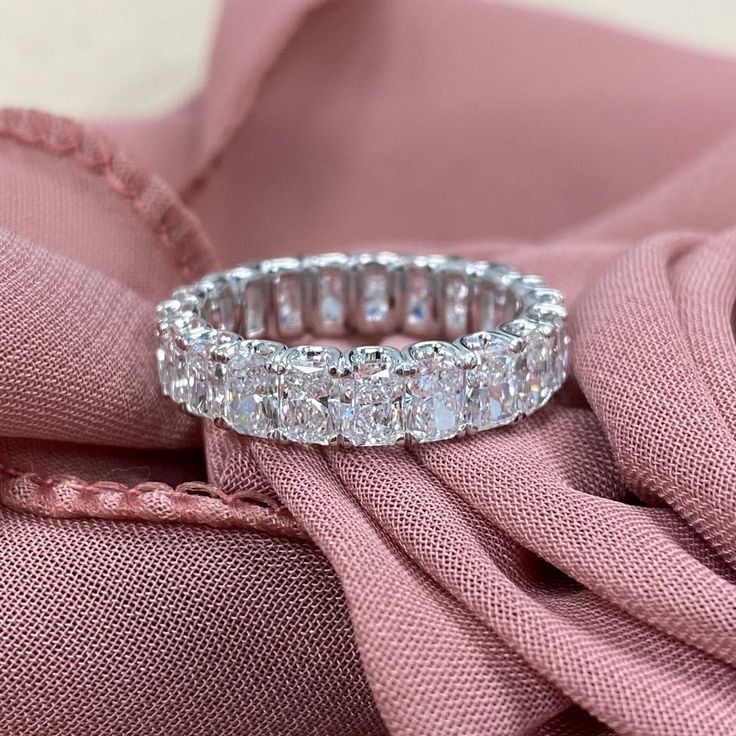 a diamond ring sitting on top of a pink cloth