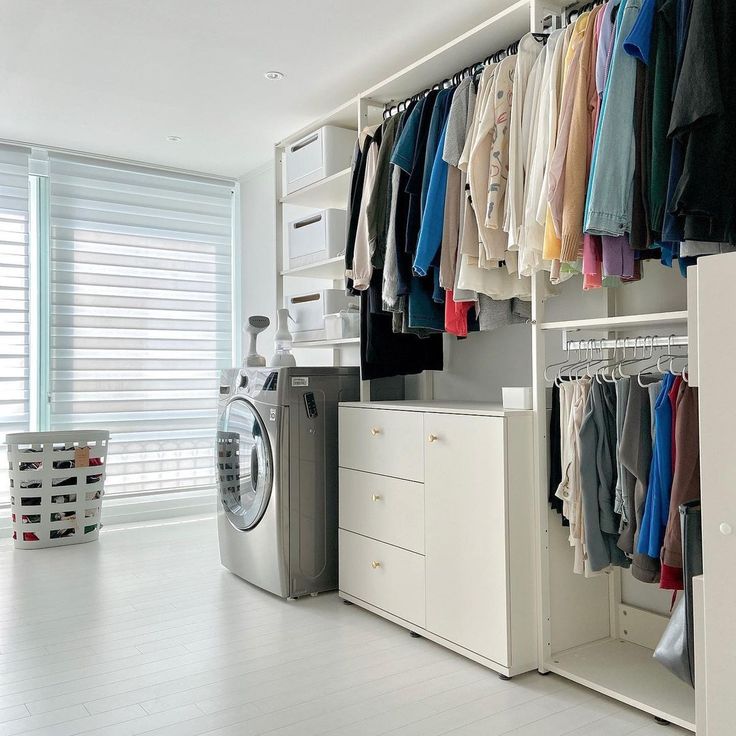 a washer and dryer in a room with clothes hanging on the wall next to it