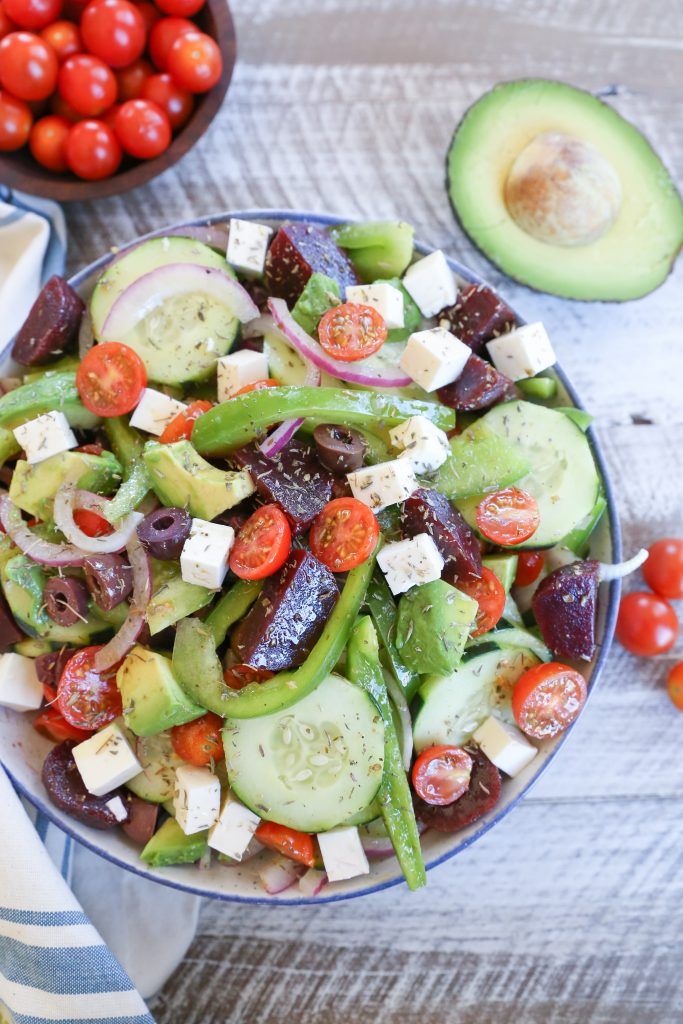 a salad with cucumbers, tomatoes, olives and feta cheese on it