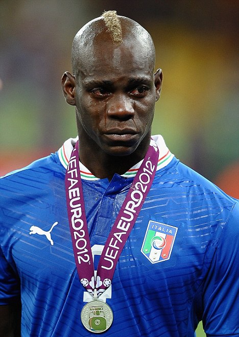 a soccer player with a medal around his neck and wearing a blue shirt is looking at the camera