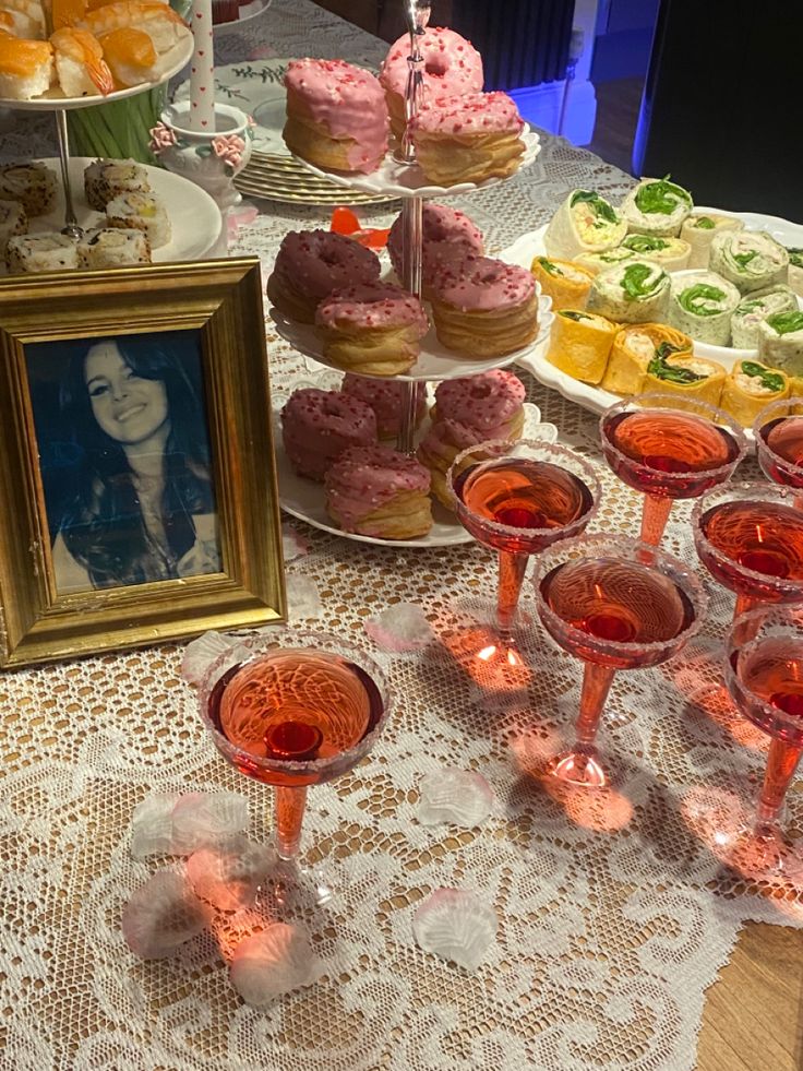 a table topped with lots of desserts and drinks next to a framed photo on top of a table