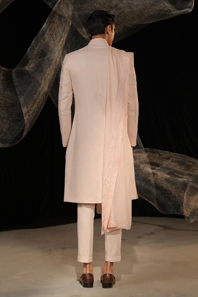 Blush pink sherwani with all over embroidery using resham and beaded work . Paired with an inner kurta and pant. Comes along with a dupatta.
Components: 4
Pattern: Embroidery
Type Of Work: Resham, Beads
Neckline: Stand Collar
Sleeve Type: Full Sleeves
Fabric: Crepe: Sherwani, Cotton Silk: Kurta and Pant
Color: Pink
Other Details: 
Embroidery on dupatta
Occasion: Destination Wedding,Groom - Aza Fashions Formal Pink Kurta With Naqshi Detailing, Pink Bandhgala With Dabka Work, Pink Long Sleeve Sherwani With Dabka Work, Pink Sherwani With Dabka Work For Eid, Pink Traditional Naqshi Sherwani, Pink Dabka Work Sherwani For Eid, Pink Nehru Jacket With Resham Embroidery, Pink Resham Embroidered Bandhgala For Formal Occasions, Pink Bandhgala With Dabka Work In Traditional Drape