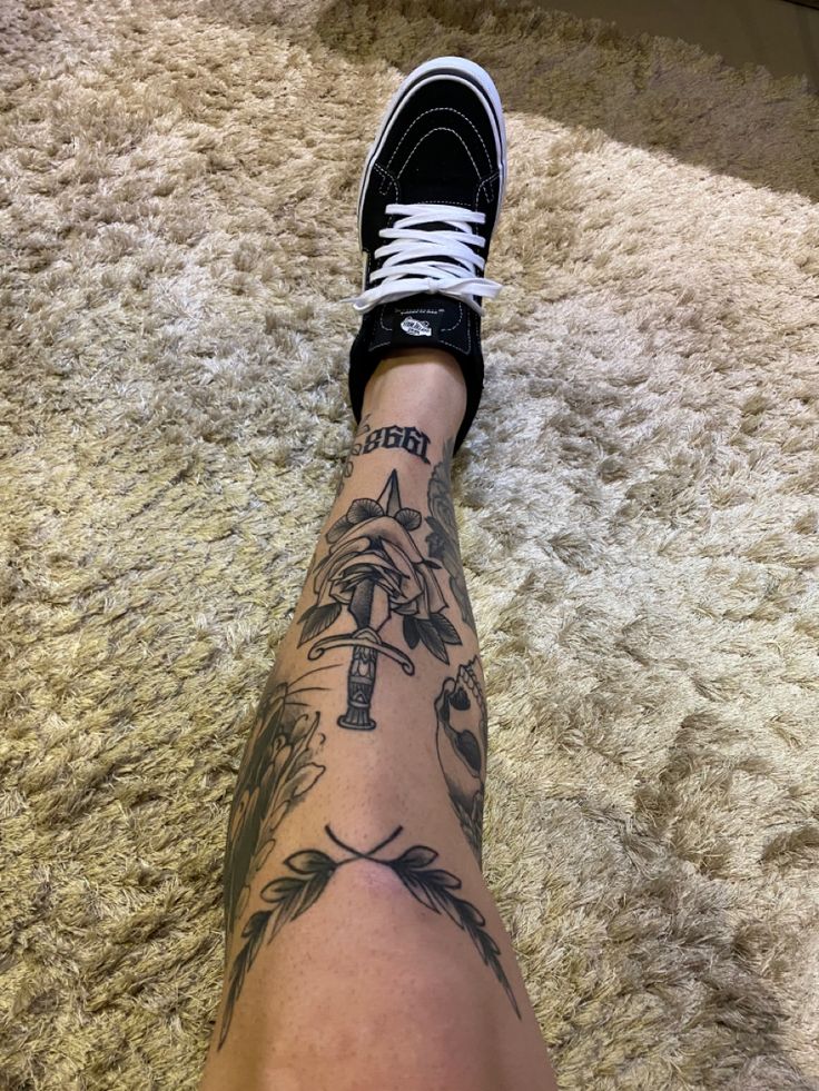 a person's foot with tattoos on it sitting on the floor next to a rug