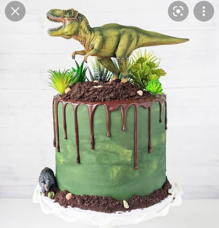 a dinosaur cake with green frosting and plants on top