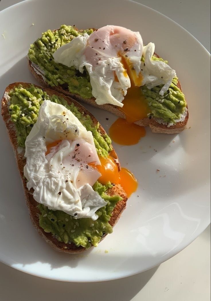 two pieces of bread with eggs and avocado on them