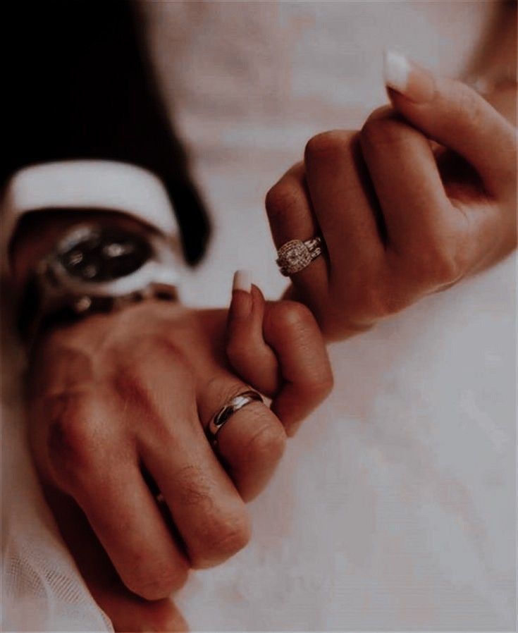 two people holding hands with wedding rings on their fingers and one is wearing a ring